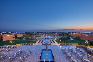 Un resort con piscina central, mobiliario exterior y vistas del paisaje circundante.
