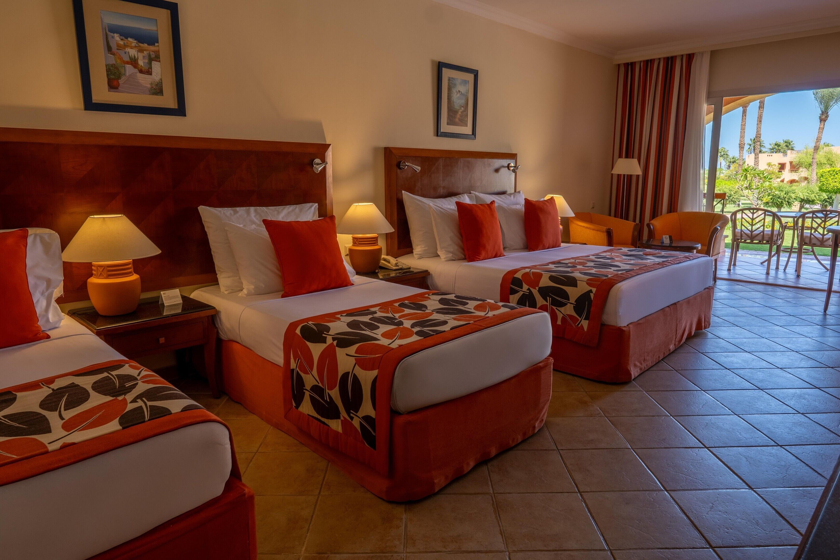 Habitación de hotel con dos camas, zona de estar y vistas al exterior.