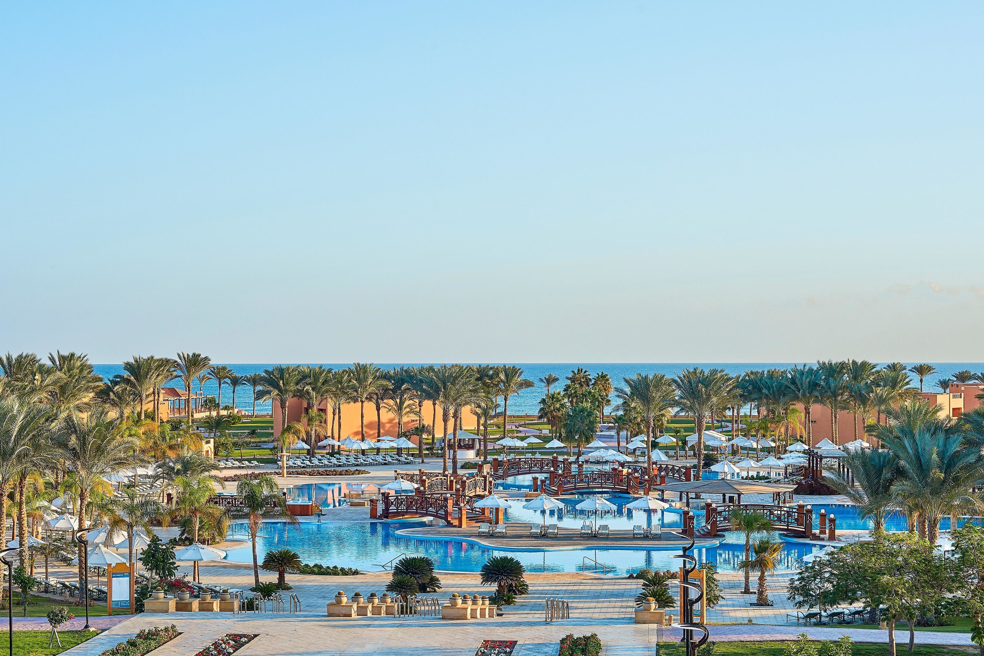 Ein Resort mit mehreren Pools, Palmen und Strandstühlen.
