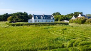A large white house with a dark roof, surrounded by a well-maintained lawn and trees. - Homerez - House in Sauzon (Sauzon)