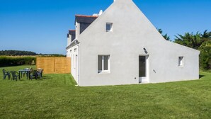 A modern house with a white exterior, a sloped roof, and a small door. - Homerez - House in Sauzon (Sauzon)