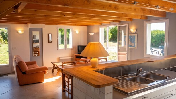 A modern kitchen with a wooden countertop, a sink, and a dining area with a sofa and table. - Homerez - House in Sauzon (Sauzon)