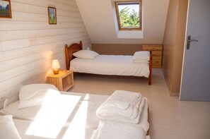 Ein Schlafzimmer mit zwei Betten, einem Fenster, einer Lampe und einer Holzwand.