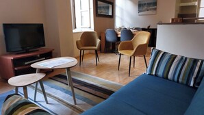 A living room with a TV, sofa, chairs, a dining table, and artwork on the walls.