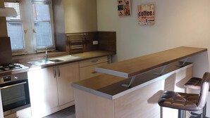 A modern kitchen with a central island, a built-in oven, and a bar area with stools.