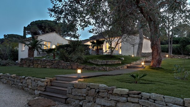 A two-story house with a stone pathway leading to the entrance, surrounded by a well-maintained lawn and trees. - Villa Paradisiaque - La HUPPE de SAINT TROPEZ (Saint-Tropez)