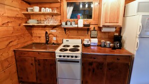 A compact kitchen with wooden cabinets, a stove, a sink, and a refrigerator.