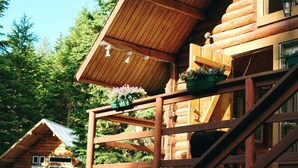 A wooden cabin with a balcony, a staircase, and a door.