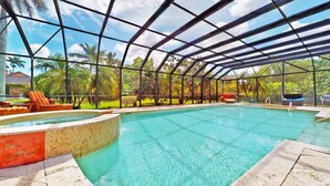 Une piscine couverte à l’eau claire, entourée d’une structure en verre, et aménagée avec des chaises longues.