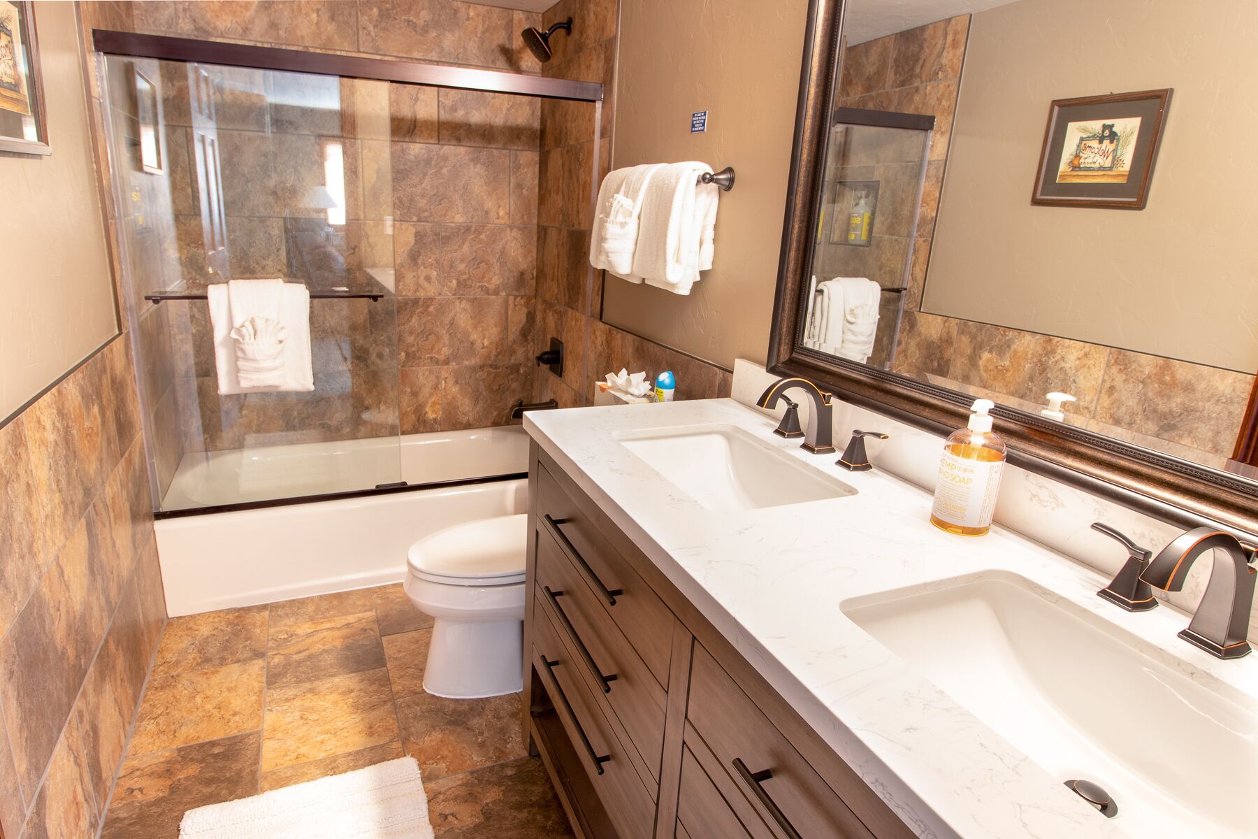 A modern bathroom with a glass-enclosed shower, a double sink vanity, and a toilet.