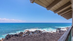 A view of the ocean from a covered balcony with a clear sky.