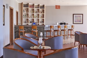Una zona de bar con encimera de piedra, sillas de madera y una amplia exhibición de licores.