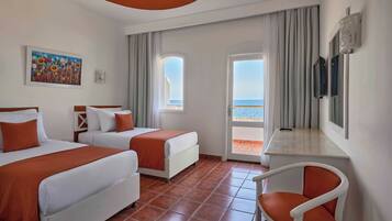 A hotel room with two beds, a desk, a chair, a TV, and a balcony with a view.