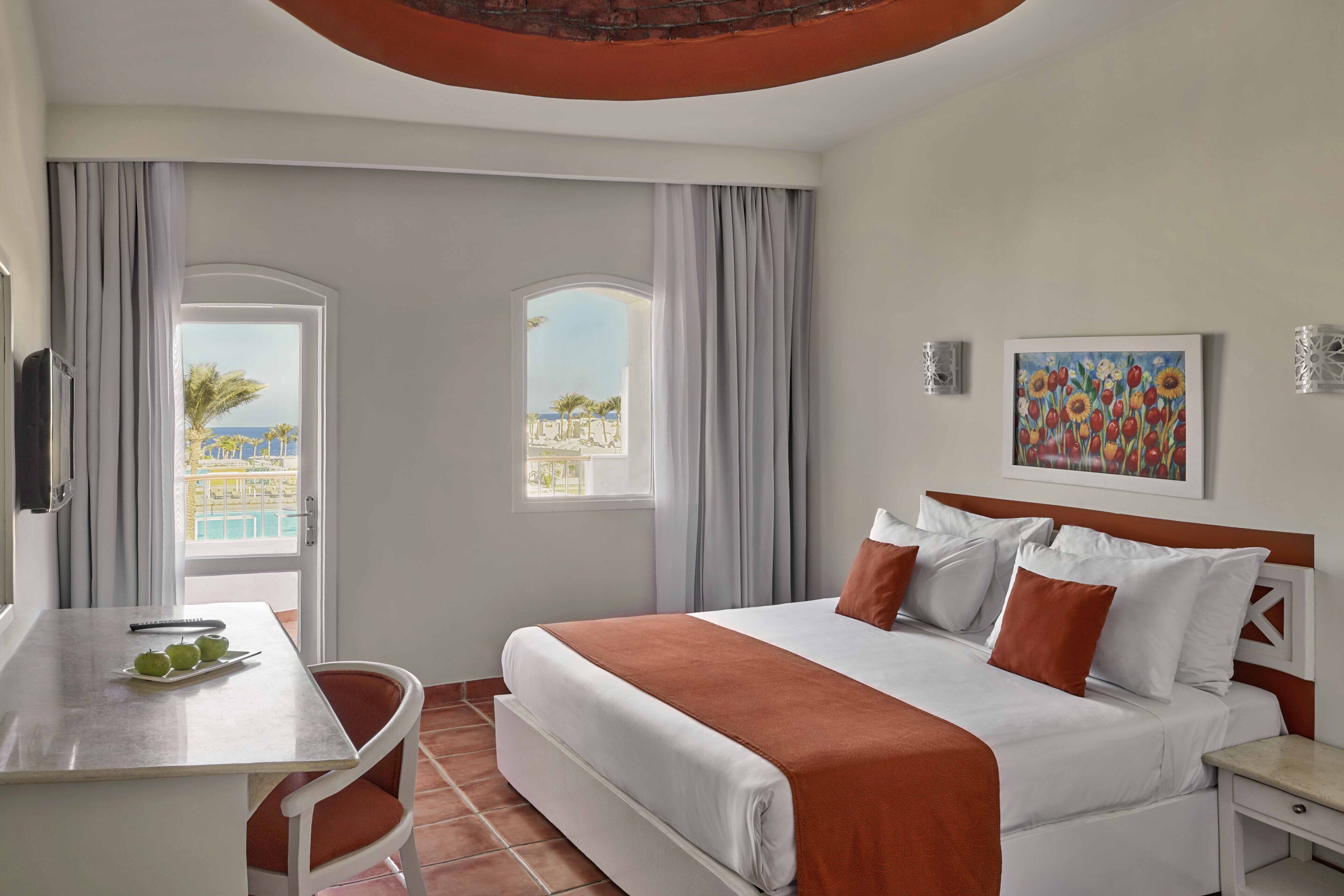Une chambre d’hôtel avec un lit, un bureau et une vue sur la piscine.