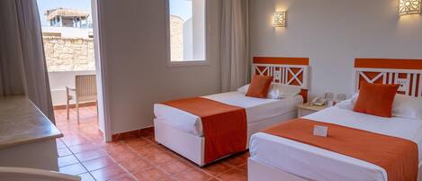 A hotel room with two beds, a desk, and a view of the outside.