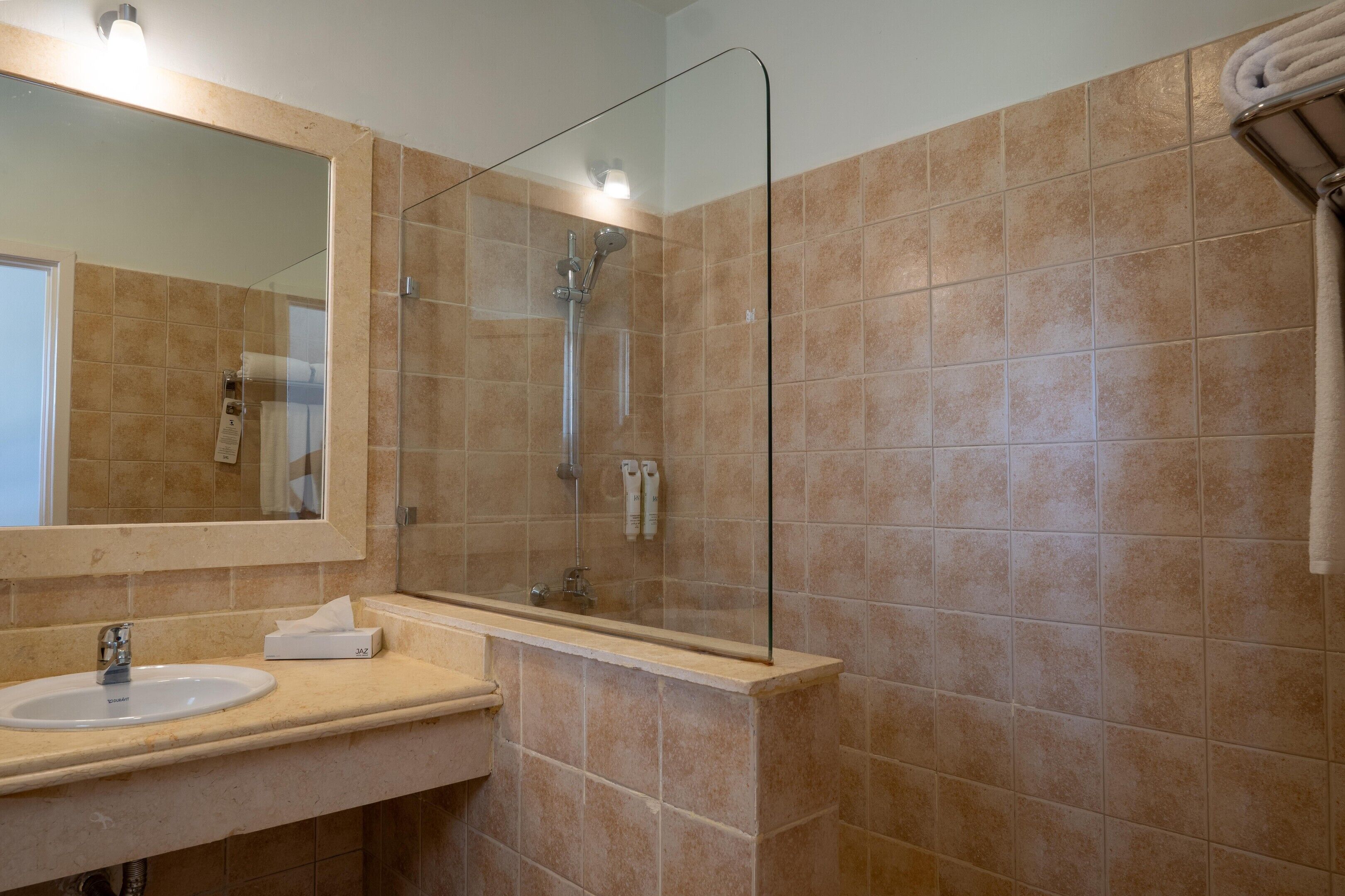 A bathroom with a glass shower enclosure, a sink with a mirror, and a towel rack.