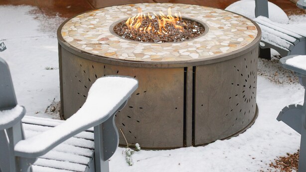 An outdoor patio with a stone fire pit, seating, a grill, and a refrigerator. - BEST YARD + HOUSE 🏡🤩Hot tub, fire pit, grill, gym, and soaking spa bathtub! (Colorado Springs)