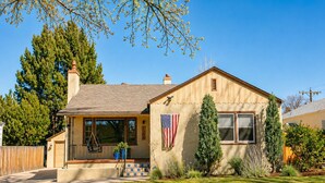 A single-story house with a front porch, a flag, and a chimney. - BEST YARD + HOUSE 🏡🤩Hot tub, fire pit, grill, gym, and soaking spa bathtub! (Colorado Springs)