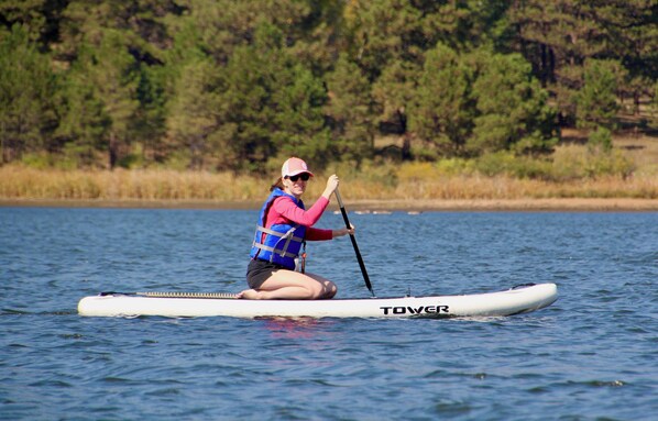 En person på et paddleboard i vand med træer i baggrunden.