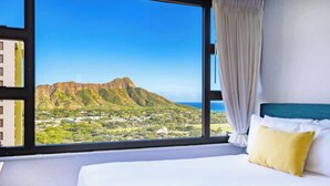 A hotel room with a large window, a bed, and a view of a mountain and landscape. - Ocean-view condo near Waikiki Beach (Honolulu)