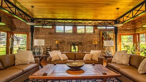 Un salon chaleureux avec une table basse en bois, deux canapés et une grande fenêtre donnant sur un paysage verdoyant.