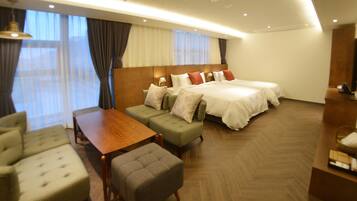 A hotel room with a large bed, a sofa, a small table, and a seating area.