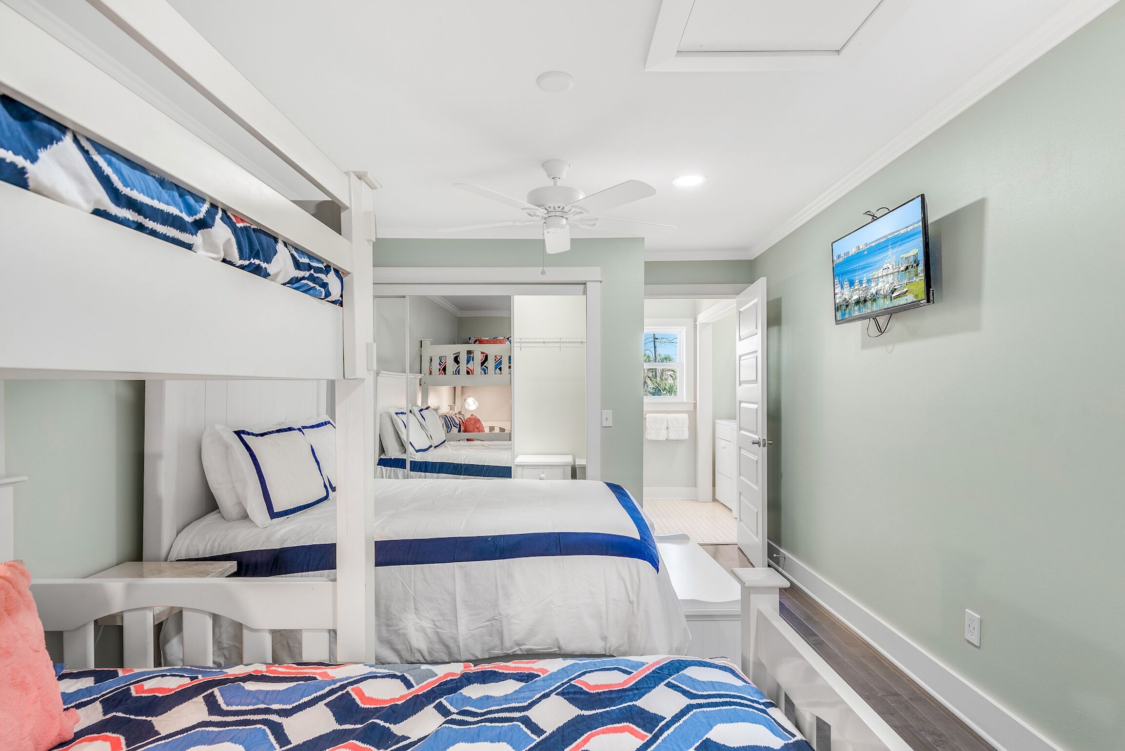 A bedroom with bunk beds, a ceiling fan, a TV, and a bathroom with a shower and toilet.