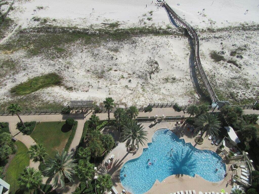 Vista aérea de um resort com uma grande piscina, palmeiras e área de praia.