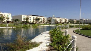 Ein Hotel am Wasserufer mit Pool, Palmen und einer Fontäne.