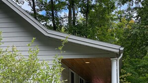 A house with a covered porch, a white chair, and pink flowering plants. - Open for the Holidays! Fireplace, Near XC skiing and Wineries, Good for Groups! (Leland)