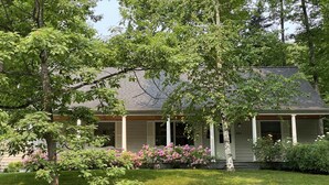 A house with a covered porch, a well-maintained lawn, and flowering bushes. - Open for the Holidays! Fireplace, Near XC skiing and Wineries, Good for Groups! (Leland)