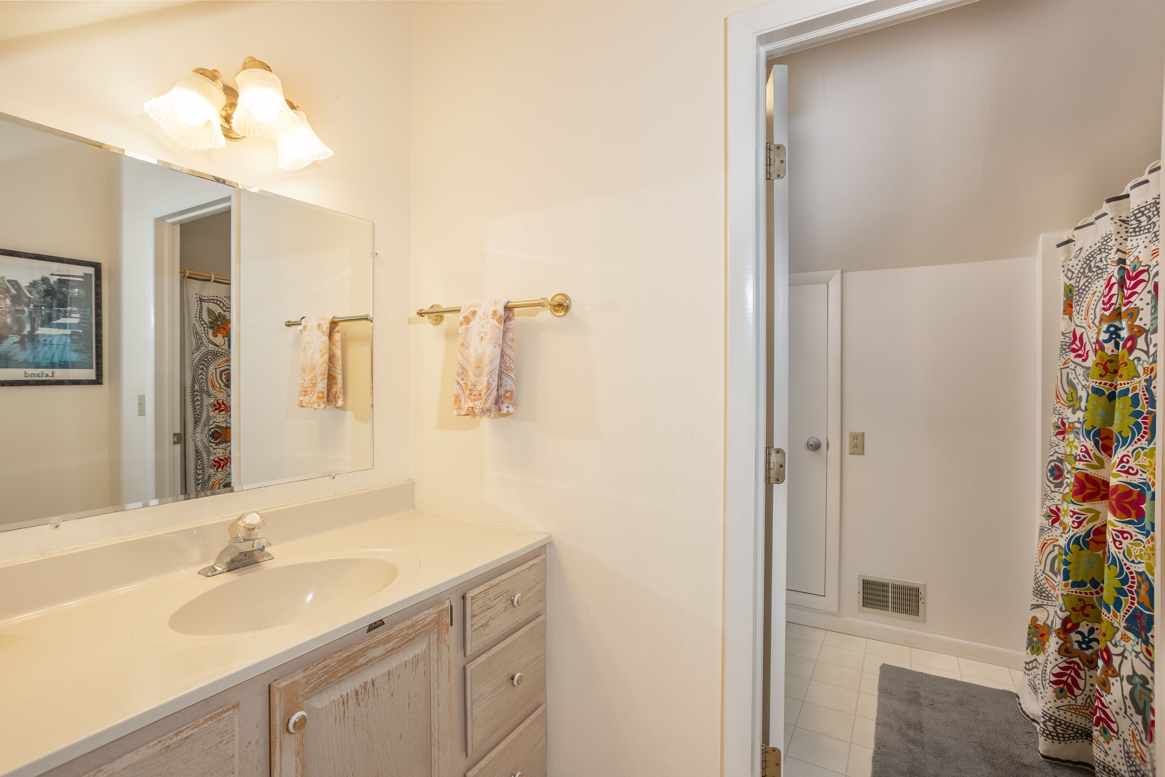 Une salle de bain équipée d’un lavabo, d’un miroir, d’un porte-serviettes et d’un rideau de douche.