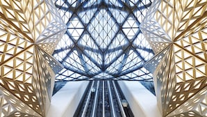Un edificio moderno con techo de vidrio geométrico y fachada simétrica.