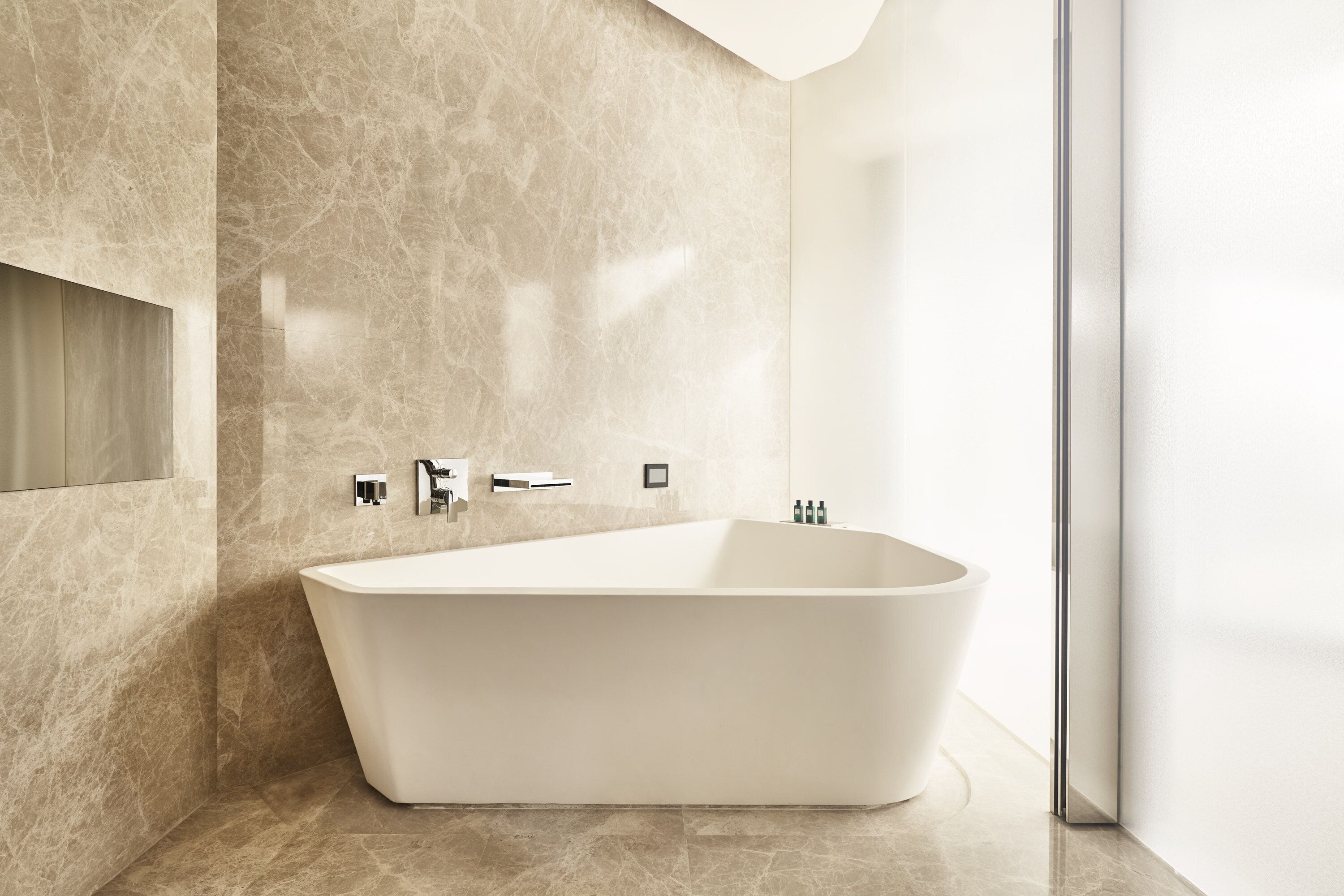 Un baño moderno con una bañera independiente, paredes de mármol y un diseño minimalista.