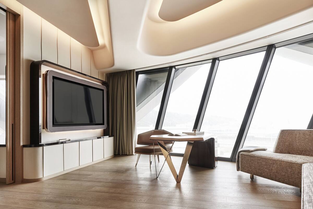 A modern living room with a large flat-screen TV, a dining table, and a sofa.