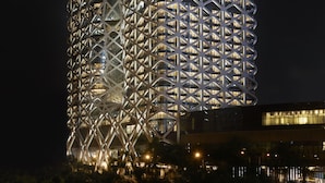 Un edificio moderno con una fachada geométrica distintiva y ventanas iluminadas al caer la noche.