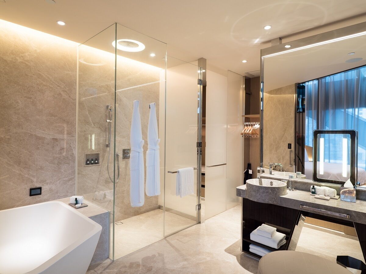 Een moderne badkamer met een douchecabine, een vrijstaand bad en een wastafel met een grote spiegel.
