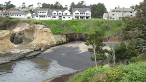 Eine Küstenlandschaft mit felsiger Uferlinie, einem Sandstrand und Wohnhäusern im Hintergrund.