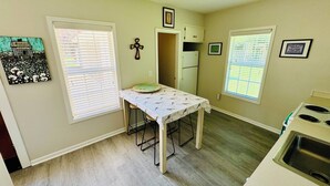 A kitchen with a table, a refrigerator, and a sink.