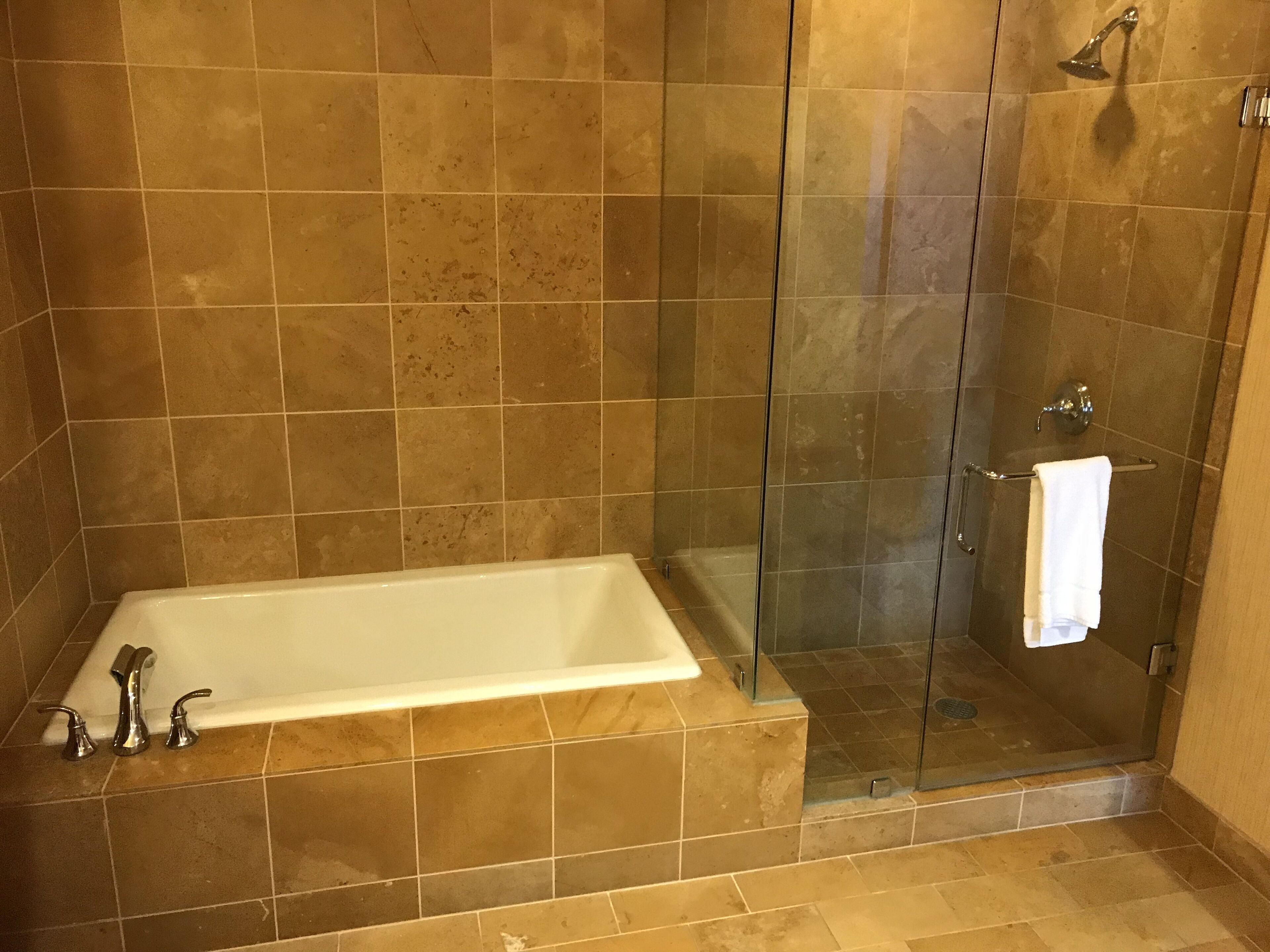 A bathroom with a bathtub, a glass shower enclosure, and a towel rack.