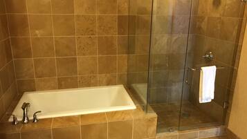 A bathroom with a bathtub, a glass shower enclosure, and a towel rack.