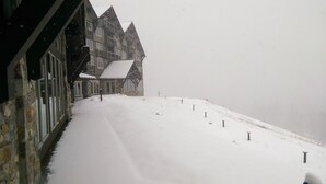 Un edificio cubierto de nieve con un camino empinado y una colina nevada.