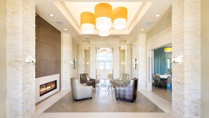 Eine geräumige Lobby mit Kamin, moderner Sitzgelegenheit und großem Fenster.