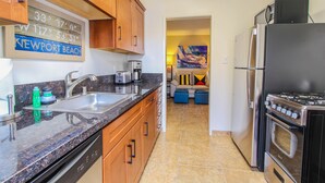 Una cocina con encimeras de granito, electrodomésticos de acero inoxidable, armarios de madera y un cuadro en la pared.