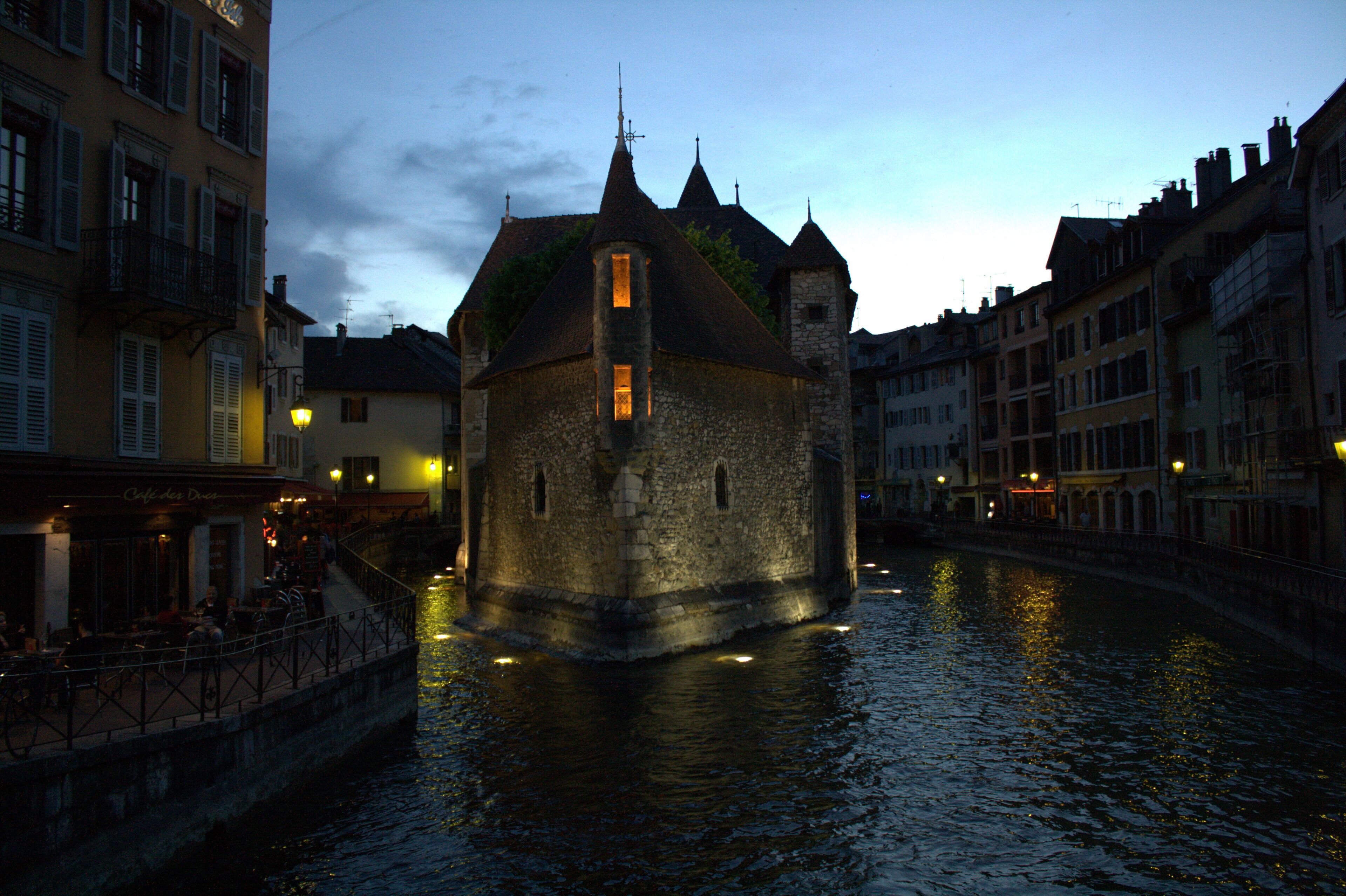 A historic building with a tower, situated by a canal.