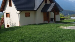 Une maison à deux étages, dotée d’un toit en pente, de fenêtres en bois et d’un petit porche.