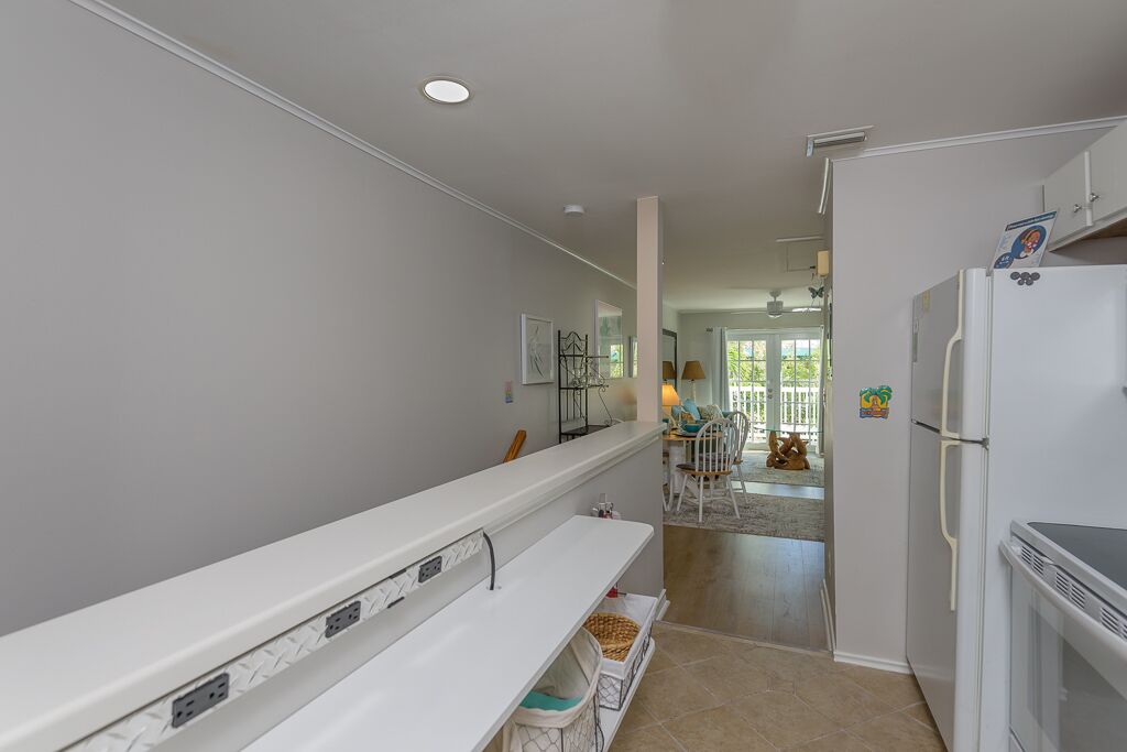 A modern kitchen with white cabinetry, a built-in bench, and a refrigerator.