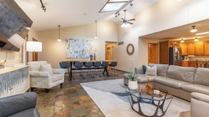 A spacious living area with a large sofa, a coffee table, and a dining table with chairs. There is a kitchen area visible in the background. - Private Pool - Pickleball - Hot Tub - Theatre Room (Branson)