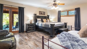 A bedroom with a bed, nightstands, a ceiling fan, a window with curtains, and a view of the outdoors. - Private Pool - Pickleball - Hot Tub - Theatre Room (Branson)