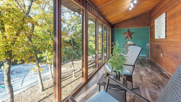 A covered outdoor seating area with large windows, a star decoration, and a wooden ceiling. - Private Pool - Pickleball - Hot Tub - Theatre Room (Branson)